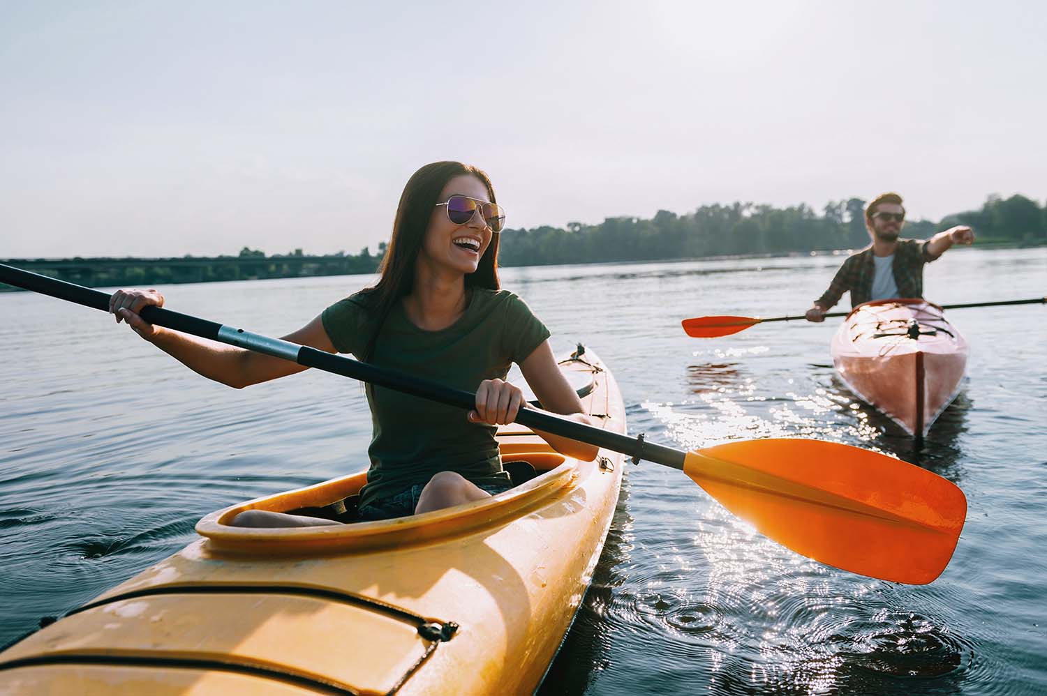 Late 20s couple happily kayaking on a holiday.